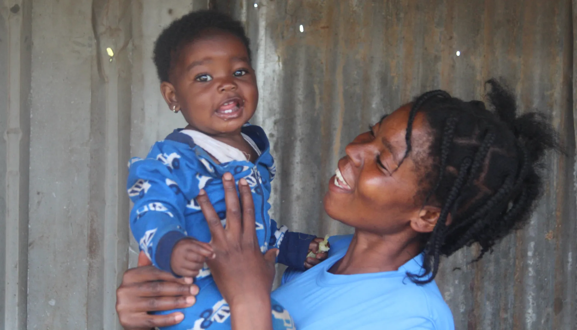 Misozi, another of three, is happy that her baby received the warm clothing.